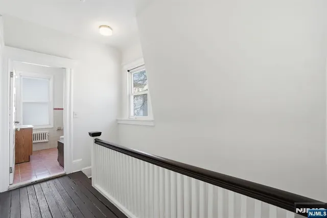 a view of a hallway with wooden floor and a bathroom