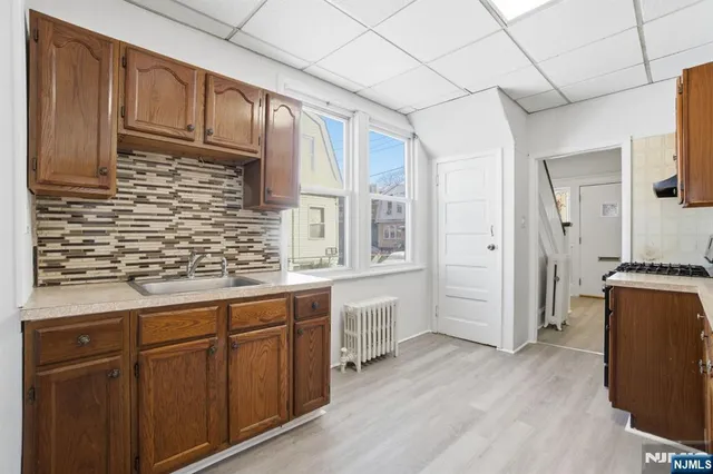 a kitchen with stainless steel appliances granite countertop a refrigerator a sink dishwasher and wooden cabinets with wooden floor