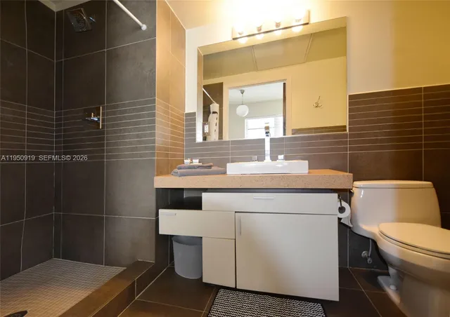 a bathroom with a sink toilet vanity and shower