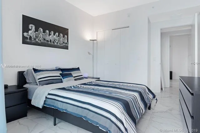 a bedroom with bed and a painting on the wall