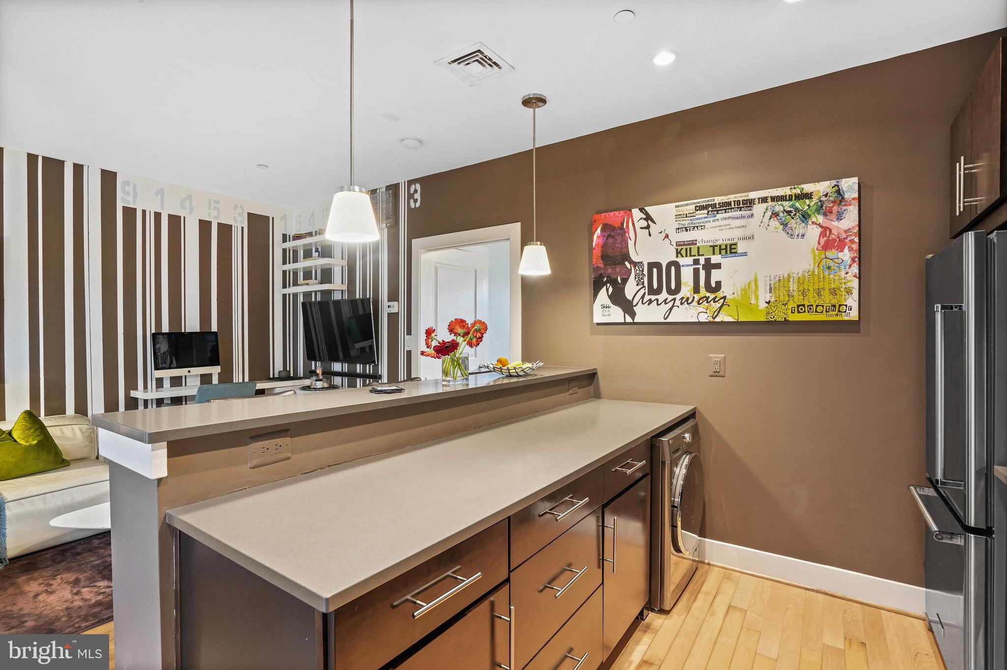 5201 B Wisconsin Avenue Northwest, Unit 105 Washington, DC 20015 - Photo 4 of 13 a view of a kitchen with kitchen island a counter top space a sink and wooden floor