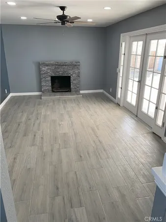an empty room with wooden floor fireplace and windows
