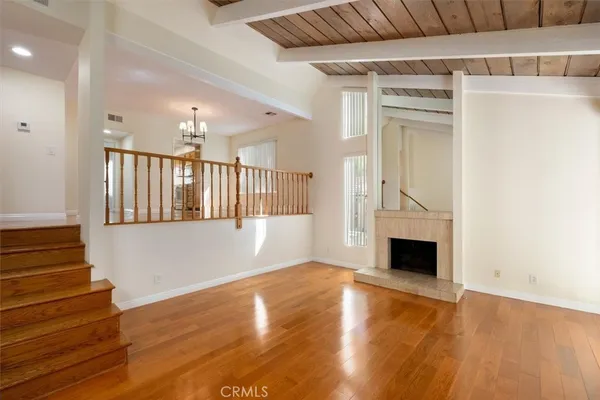 a view of an empty room with wooden floor and a fireplace