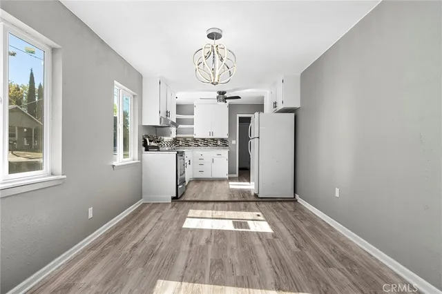 a view of kitchen and empty room with wooden floor