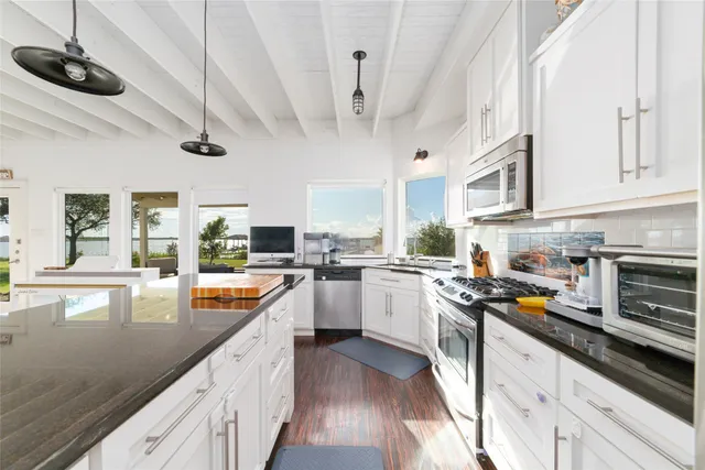 a large white kitchen with lots of counter space and refrigerator