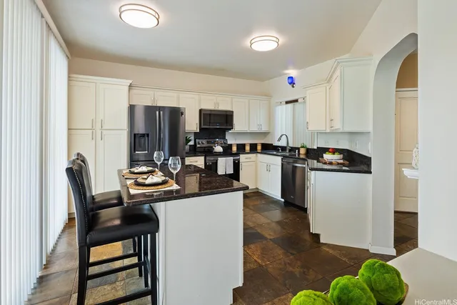 a kitchen view with kitchen island granite countertop a stove top oven a sink a dining table and chairs