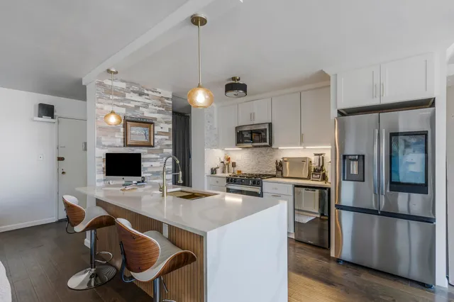 a kitchen with stainless steel appliances granite countertop a stove refrigerator a sink dishwasher a dining table and chairs with wooden floor