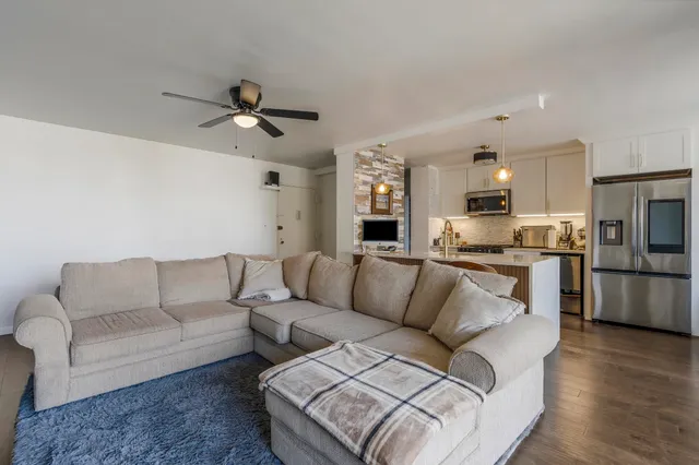 a living room with furniture and a large window with kitchen view