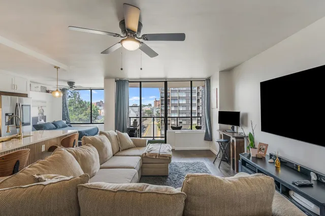 a living room with furniture and a large window with kitchen view
