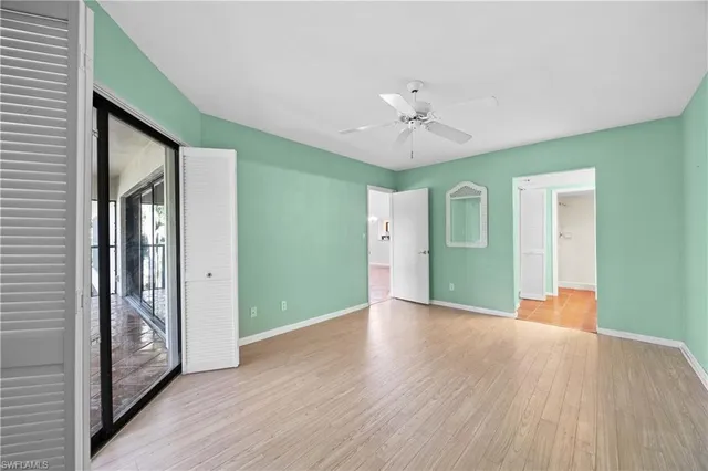 a view of an empty room with window wooden floor and a kitchen