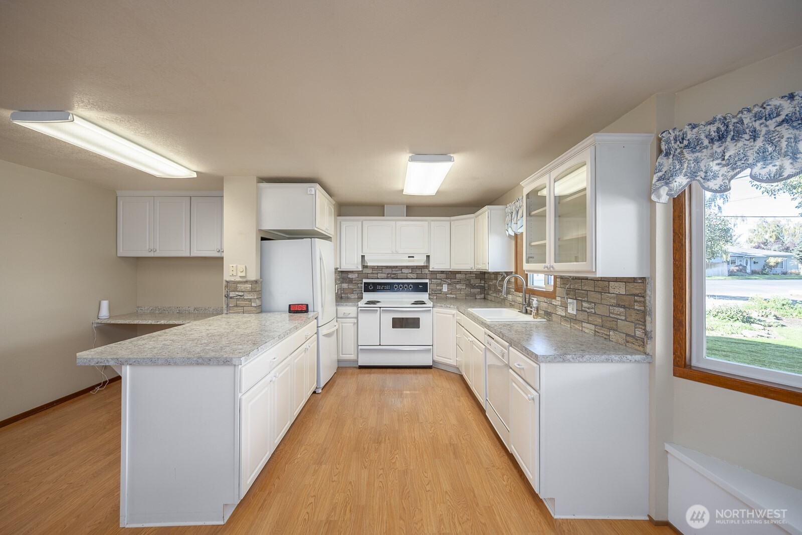 221 K Street Southwest Quincy, WA 98848 - Photo 17 of 38 a large white kitchen with cabinets a sink a window and stainless steel appliances