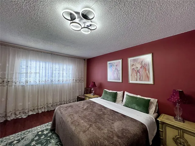 a bedroom with a bed a dresser and flat screen tv