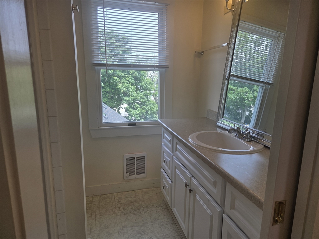 14 Hawkes Street, Unit 2 Marblehead, MA 01945 - Photo 12 of 12 a bathroom with a granite countertop sink a window and a mirror