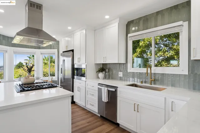 a kitchen with stainless steel appliances granite countertop a stove a sink and a white cabinets