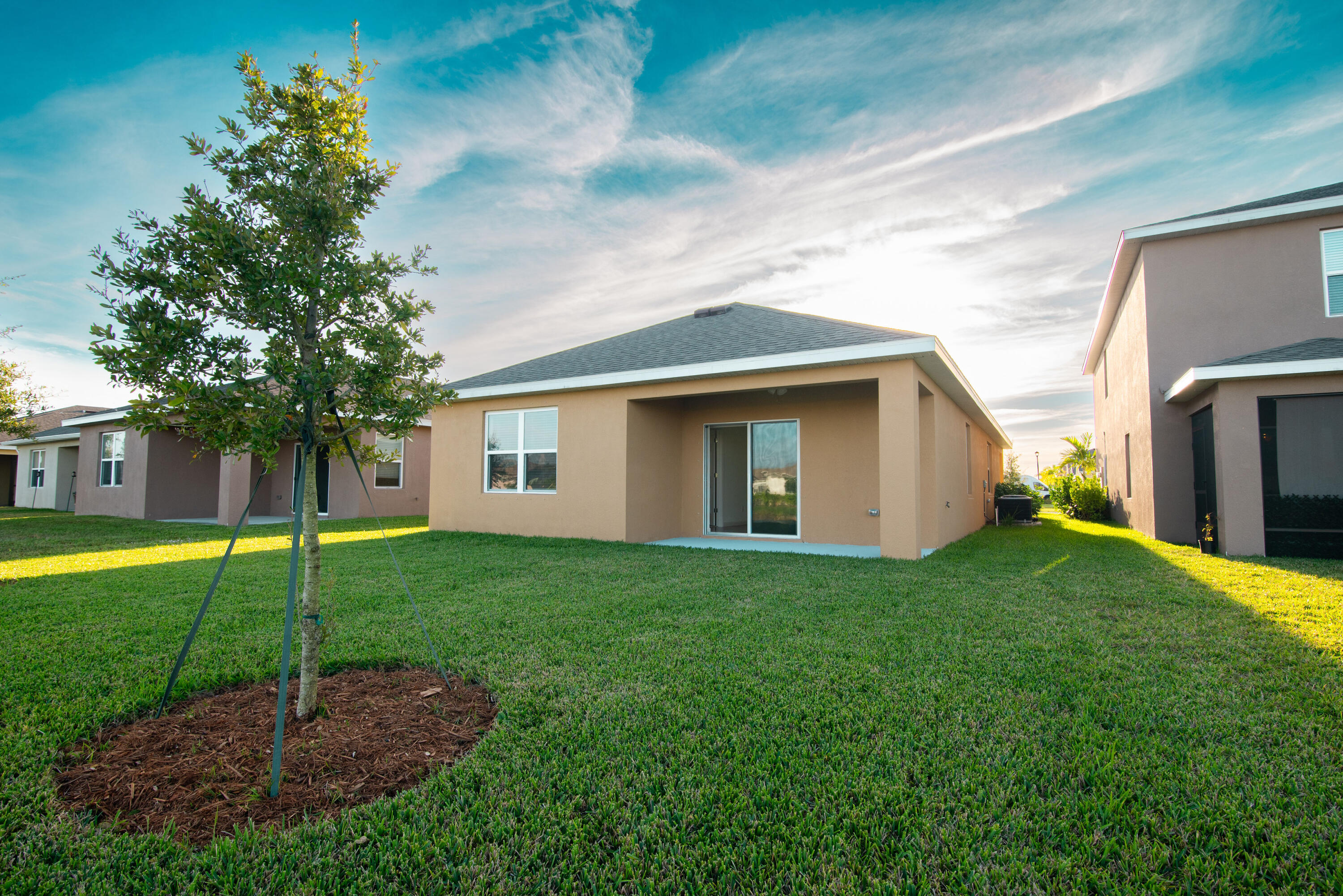 12152 Rimini Way Port St. Lucie, FL 34987 - Photo 18 of 24 a backyard of a house with plants and large tree