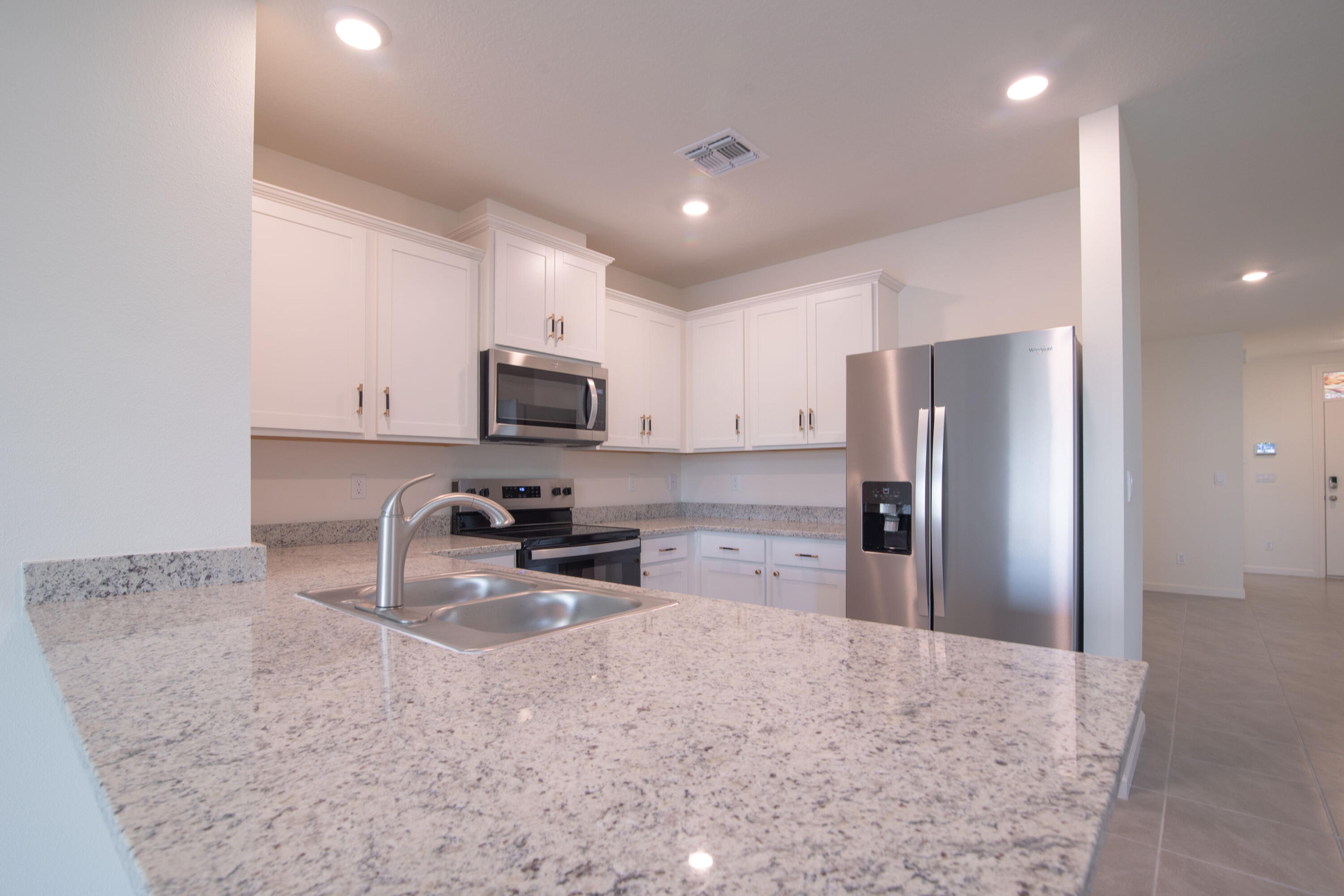 12152 Rimini Way Port St. Lucie, FL 34987 - Photo 4 of 24 a kitchen with stainless steel appliances granite countertop a refrigerator a stove a sink a microwave and a refrigerator