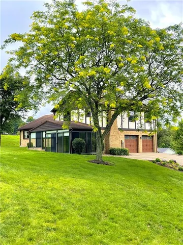 a view of a house with a big yard and large trees