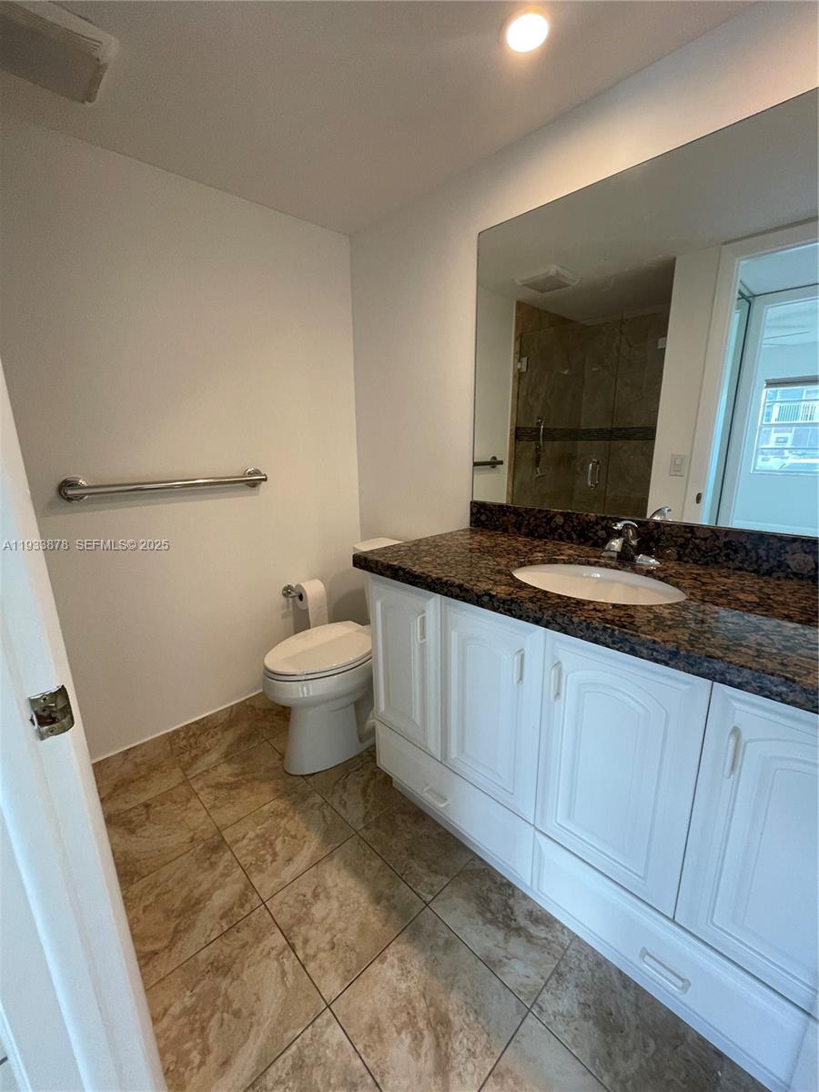 485 Flanders P, Unit 485 Delray Beach, FL 33484 - Photo 23 of 42 a bathroom with a toilet sink and mirror