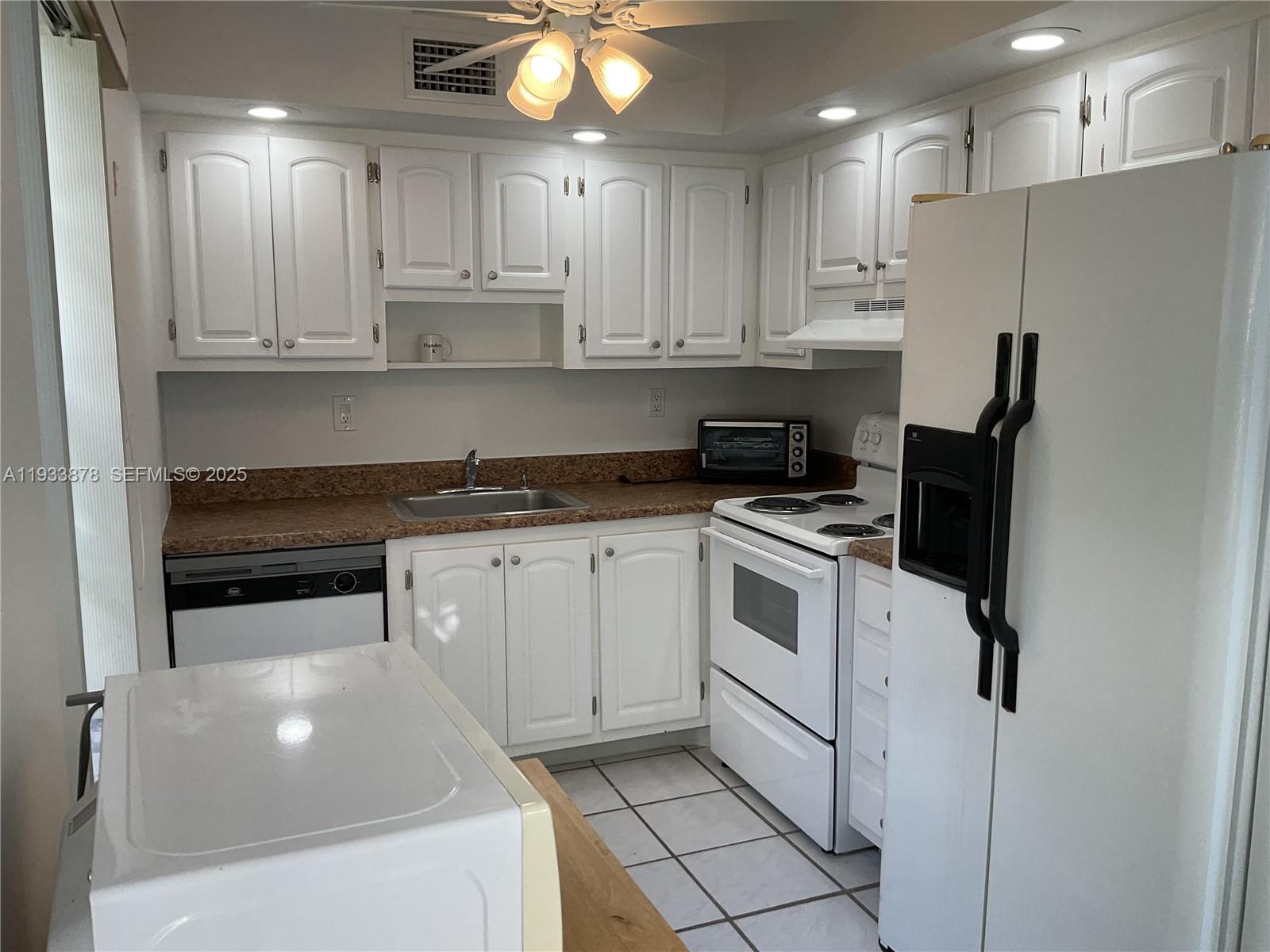 485 Flanders P, Unit 485 Delray Beach, FL 33484 - Photo 7 of 42 a kitchen with white cabinets and white appliances