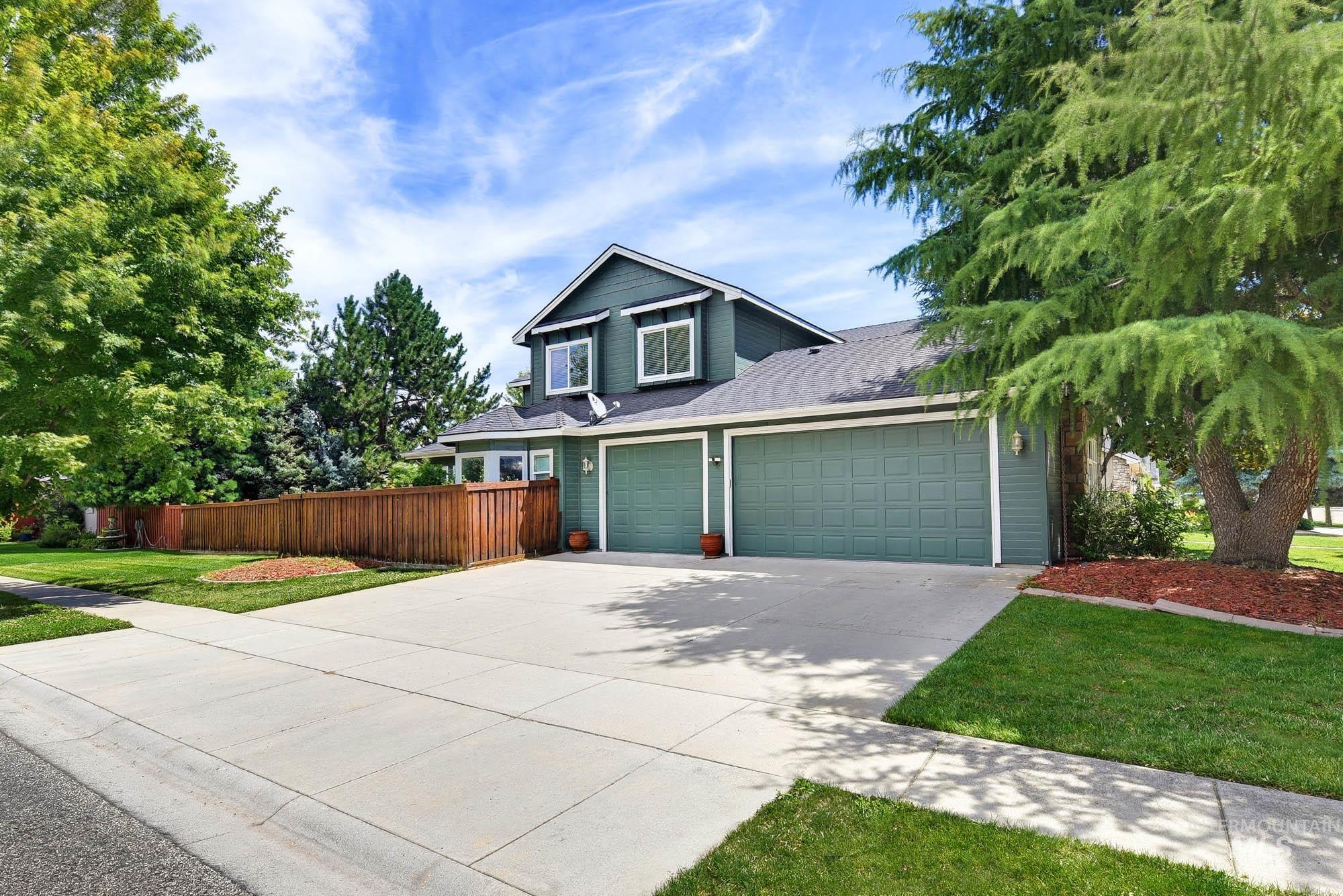 2172 West Cedar Grove Street Meridian, ID 83646 - Photo 2 of 49 Two-story residence featuring a two-car garage with green doors, a spacious concrete driveway, and a wood privacy fence