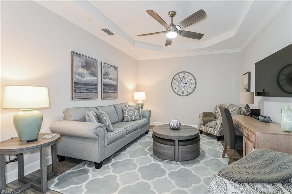 9636 Montelanico Loop, Unit 101 Naples, FL 34119 - Photo 4 of 10 Living room with a tray ceiling, crown molding, ceiling fan, and light wood-style flooring