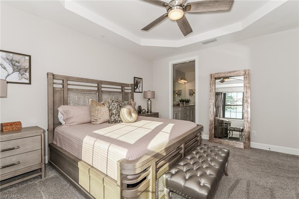 9636 Montelanico Loop, Unit 101 Naples, FL 34119 - Photo 8 of 10 Carpeted bedroom featuring a raised ceiling, a ceiling fan, and ensuite bathroom