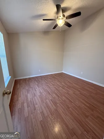 an empty room with wooden floor fan and windows