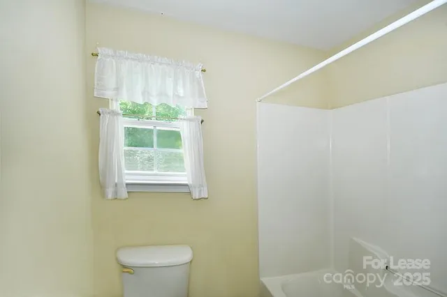 a bathroom with a window a toilet and a window