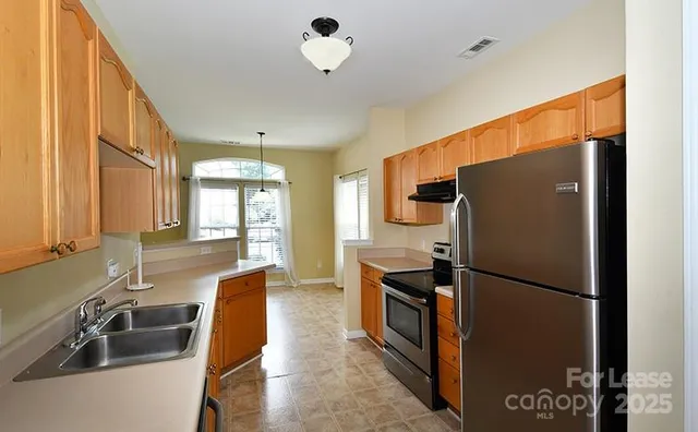 a kitchen with stainless steel appliances granite countertop a refrigerator a sink and a stove