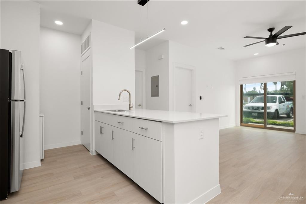 412 South Ware Road McAllen, TX 78501 - Photo 6 of 7 Kitchen with stainless steel refrigerator, light wood-type flooring, ceiling fan, hanging light fixtures, and sink