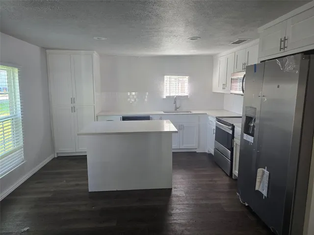 a kitchen with kitchen island white cabinets and stainless steel appliances