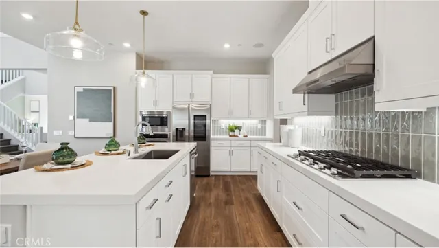 a kitchen with stainless steel appliances a sink a stove a refrigerator and cabinets