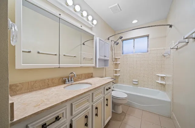 a bathroom with a granite countertop sink a toilet a mirror and shower