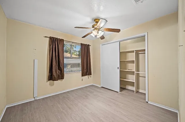 a view of empty room with wooden floor and fan