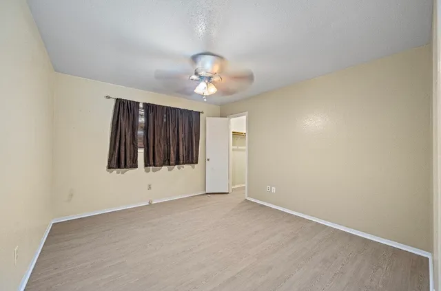an empty room with ceiling fan and window
