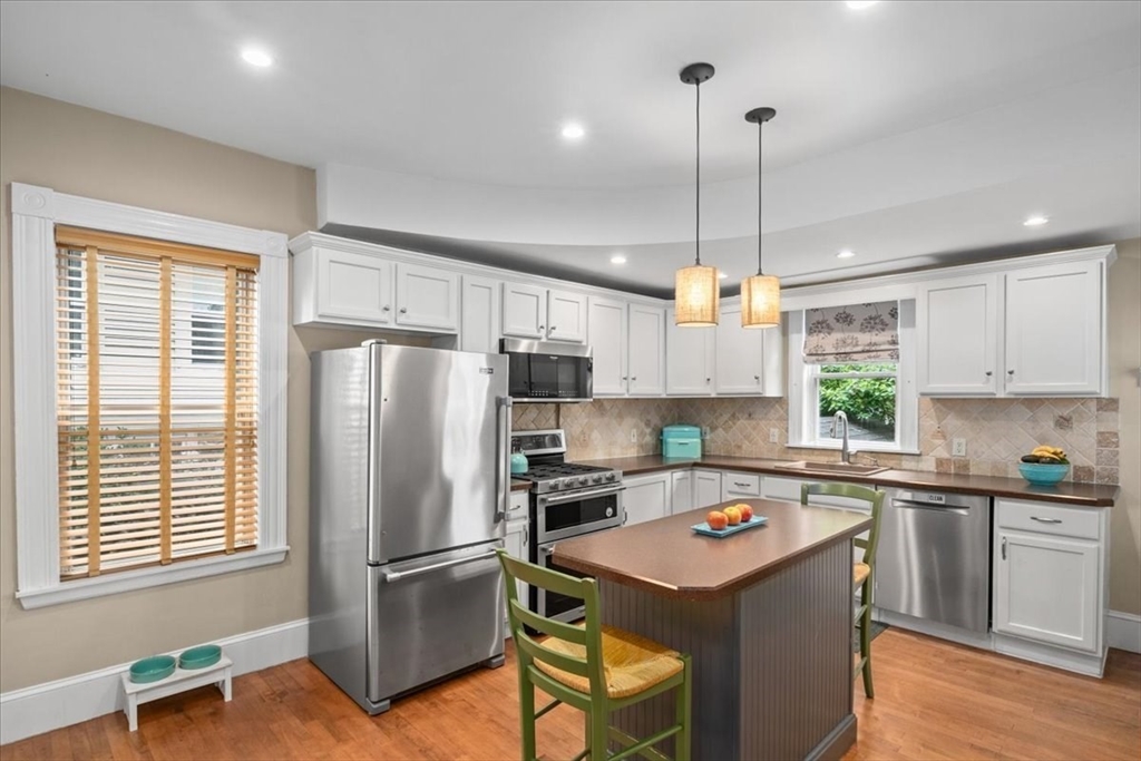 265 Sutton Street North Andover, MA 01845 - Photo 7 of 27 a kitchen with kitchen island a sink a counter top space stainless steel appliances and windows