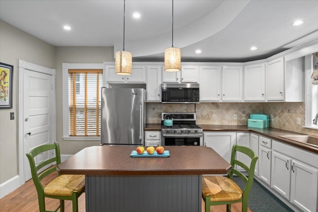 265 Sutton Street North Andover, MA 01845 - Photo 8 of 27 a kitchen with stainless steel appliances granite countertop a sink a stove a refrigerator a microwave a dining table and chairs