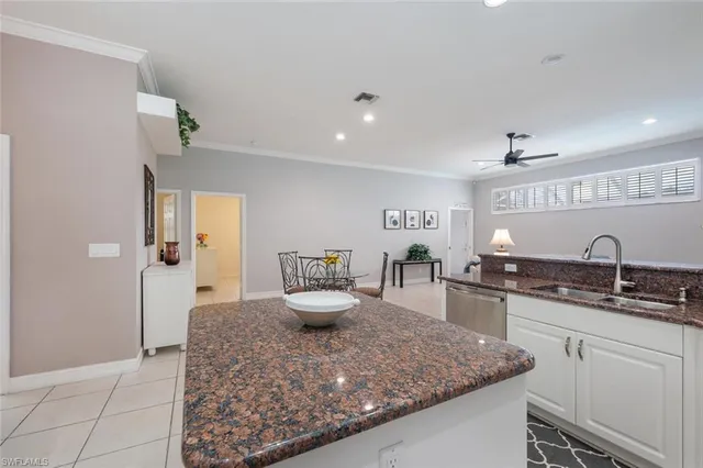 a kitchen with kitchen island granite countertop a sink and white cabinets