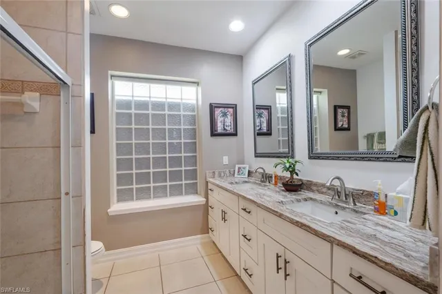 a spacious bathroom with a double vanity sink a large mirror and a shower
