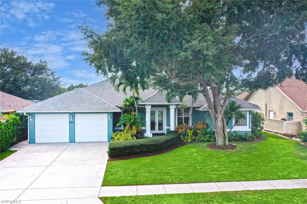 9974 Boca Avenue North Naples, FL 34109 - Photo 4 of 42 a front view of a house with a garden and trees