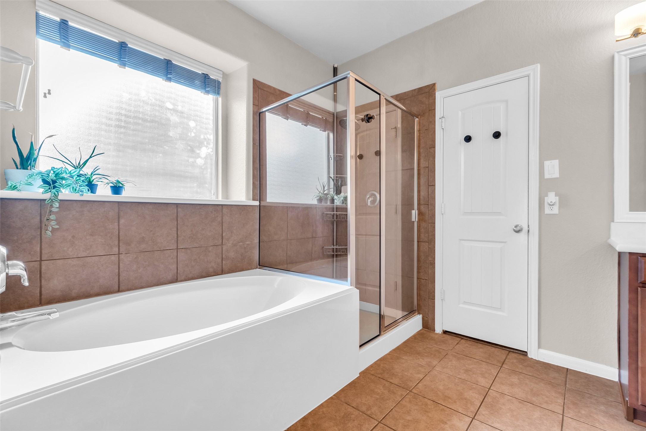 155 Magnolia Grove Lane Conroe, TX 77384 - Photo 12 of 25 Primary bathroom features a modern design with a large soaking tub, a separate glass-enclosed shower, and neutral tile flooring. A frosted window provides natural light.