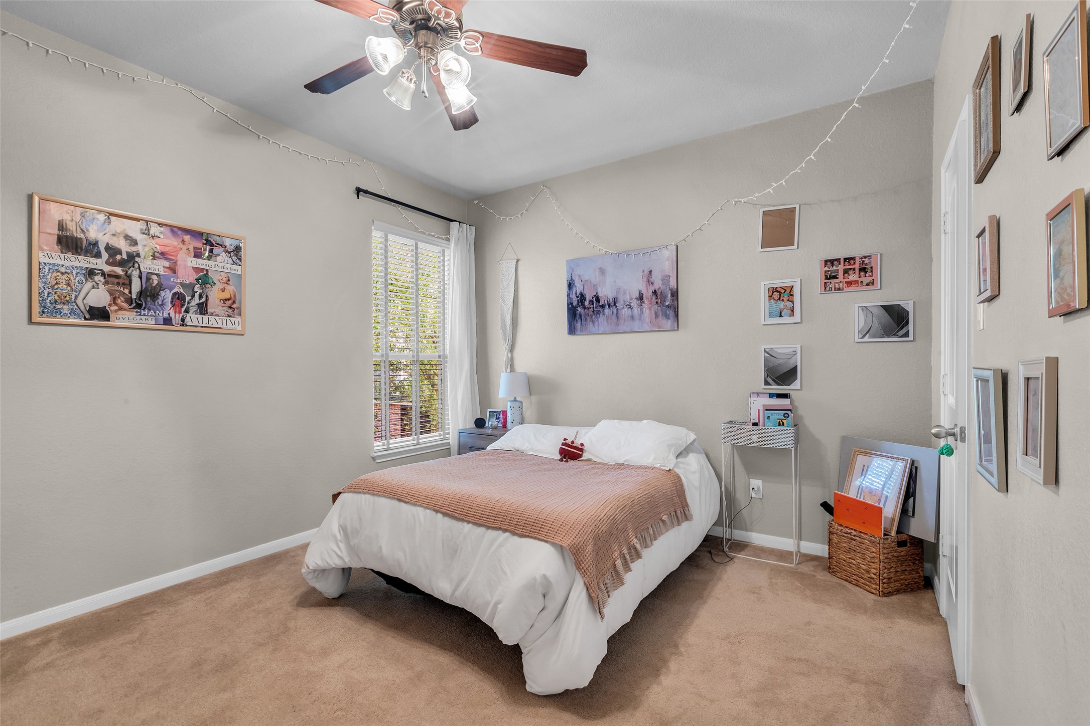 155 Magnolia Grove Lane Conroe, TX 77384 - Photo 17 of 25 Cozy 2nd bedroom with neutral walls and carpet, featuring a ceiling fan and ample natural light through a window with blinds.