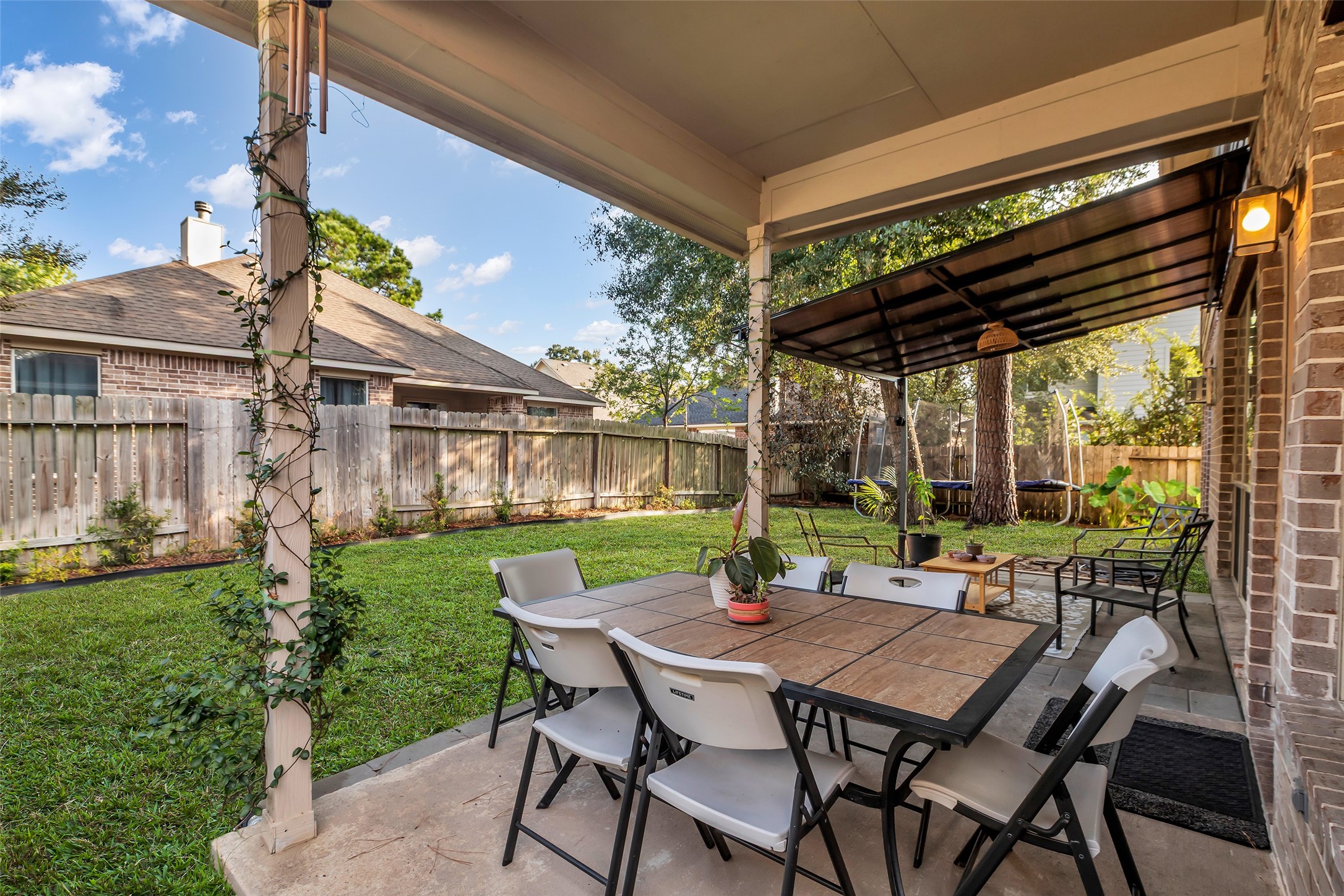 155 Magnolia Grove Lane Conroe, TX 77384 - Photo 22 of 25 Backyard features a covered patio with a dining set, a cozy seating area, and lush greenery, perfect for outdoor gatherings and relaxation.