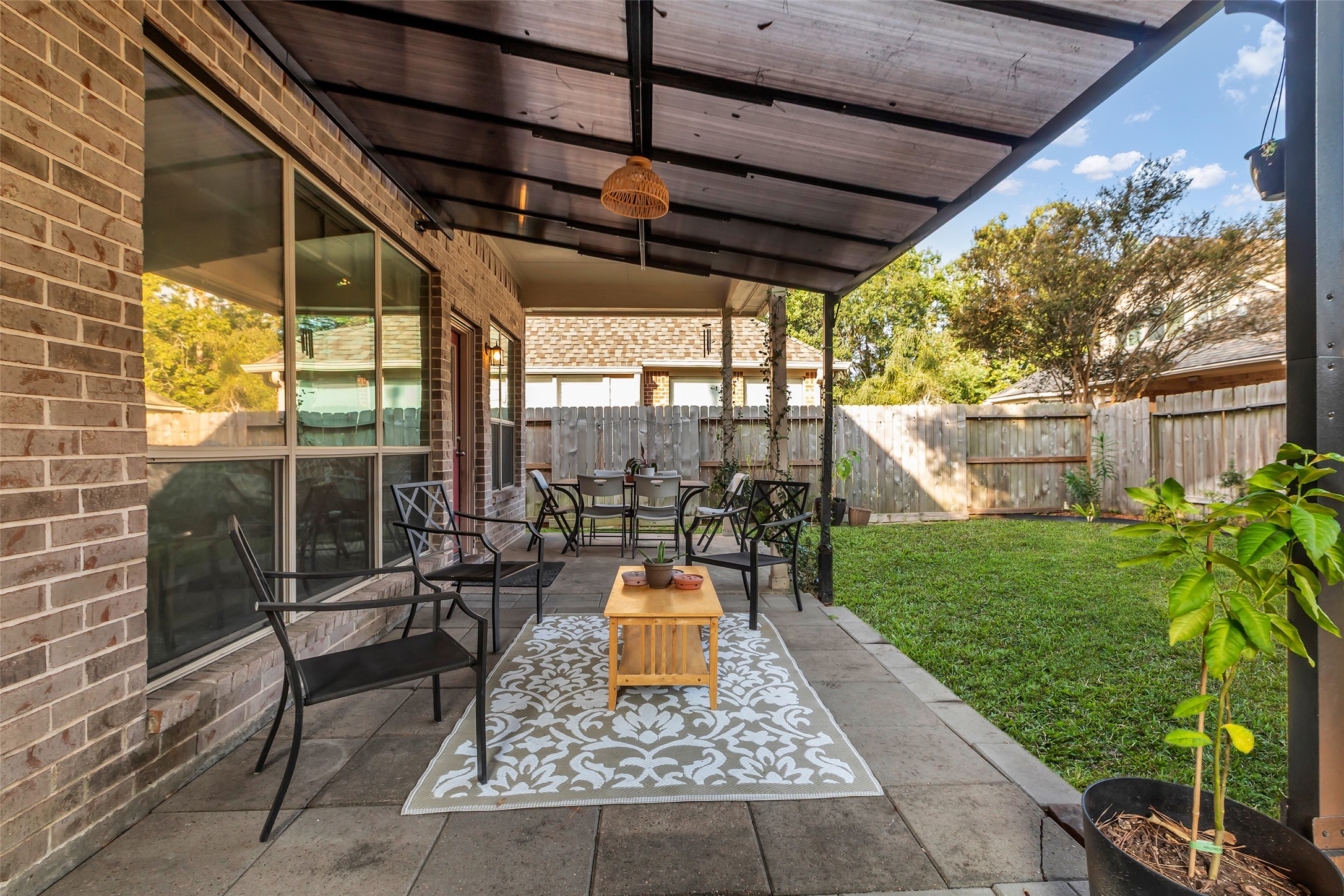 155 Magnolia Grove Lane Conroe, TX 77384 - Photo 23 of 25 Covered patio with a seating area, ideal for outdoor relaxation. It opens to a private fenced backyard with lush grass, perfect for family gatherings or enjoying quiet mornings.