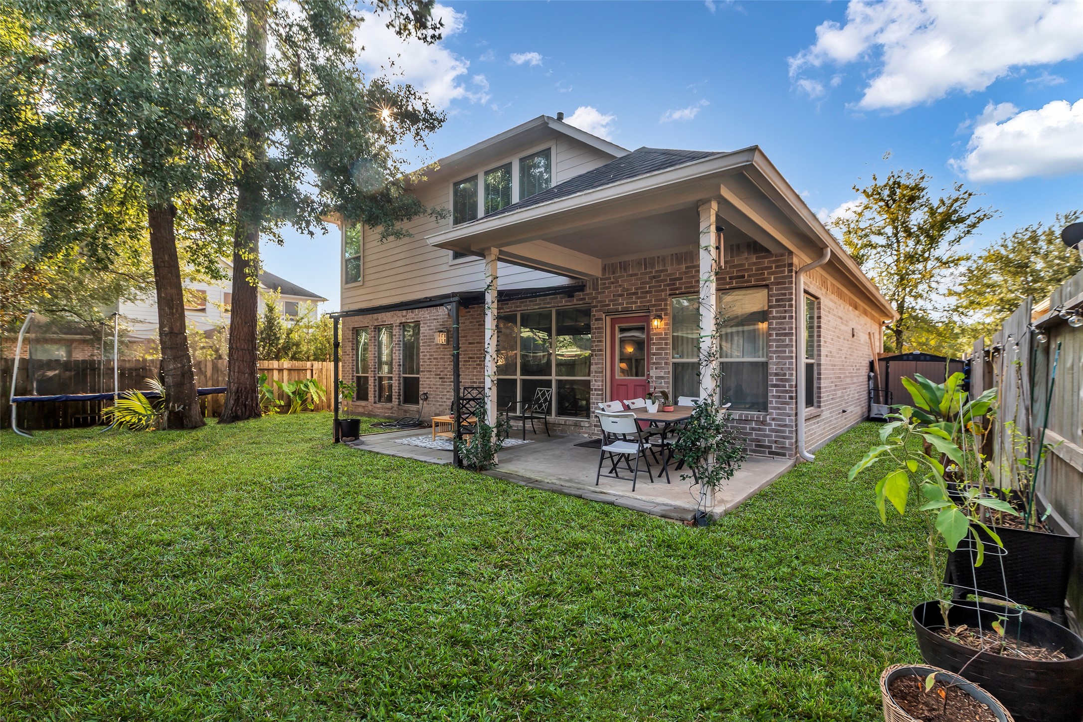 155 Magnolia Grove Lane Conroe, TX 77384 - Photo 24 of 25 Backyard with a spacious lawn, a covered patio featuring outdoor seating, and mature trees providing shade.