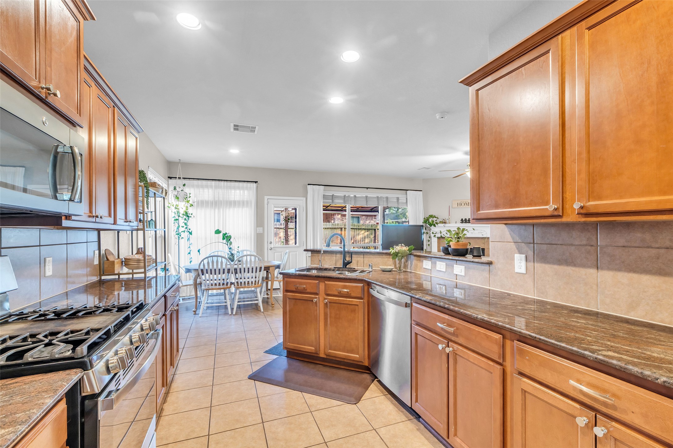 155 Magnolia Grove Lane Conroe, TX 77384 - Photo 9 of 25 Kitchen opens to a bright dining area with large windows, offering a welcoming and functional space for cooking and entertaining.