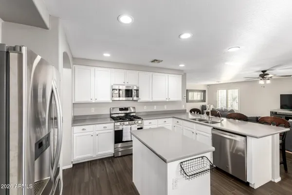 a kitchen with a stove a sink dishwasher a refrigerator and white cabinets with wooden floor