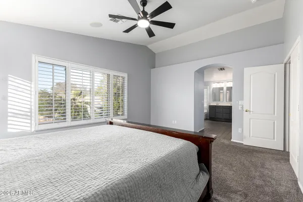 a bedroom with a large bed and a chandelier fan
