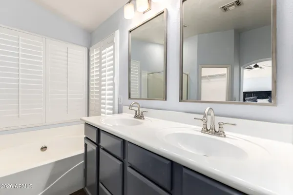 a bathroom with a double vanity sink mirror and a bathtub
