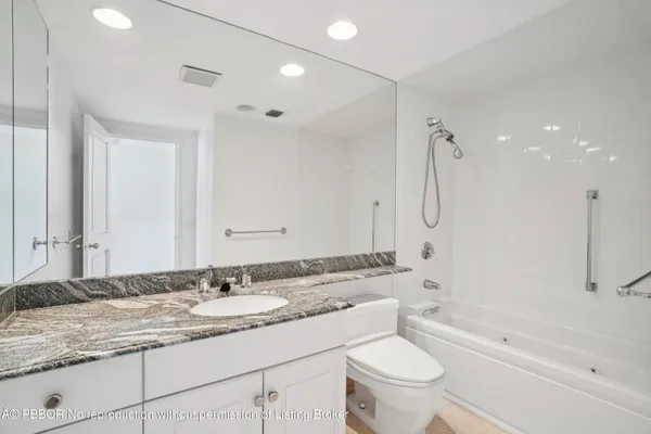 a bathroom with a granite countertop sink a toilet and shower